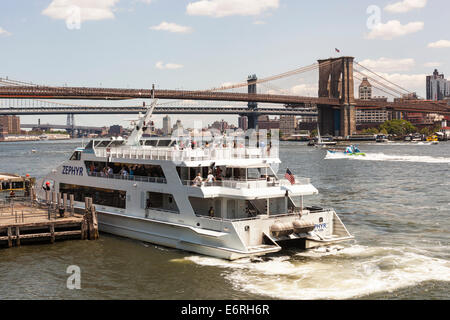 Pleasure boat on East River beside Brooklyn Bridge and South Street Seaport, Manhattan, New York City, New York, USA Stock Photo