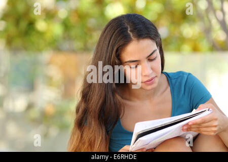 Beautiful student teen girl studying outdoor in a park with a green background Stock Photo