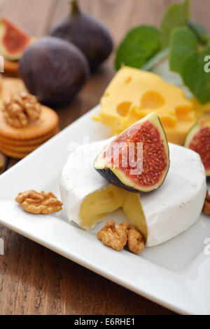 Camembert cheese with walnuts and fresh figs on wooden background Stock Photo