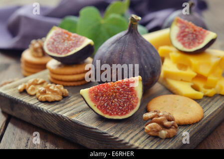 Fresh figs with walnuts and crackers on wooden background Stock Photo