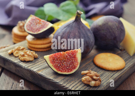 Fresh figs with walnuts and crackers on wooden background Stock Photo