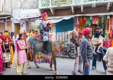 Traditional wedding procession in Deogarh, Rajasthan: the groom and his young brother ride through the streets on horseback with his family Stock Photo