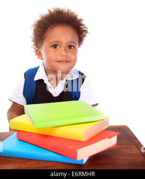 Portrait of cute little boy wearing school uniform with many colorful books isolated on white background, doing homework Stock Photo