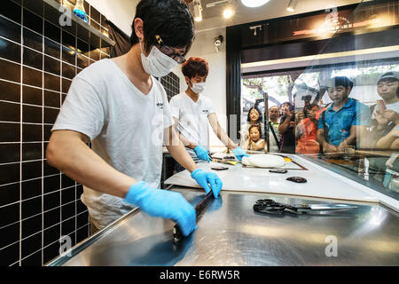 (140830) -- BEIJING, Aug. 30, 2014 (Xinhua) -- Chen Jingchao (L) and one of his apprentices make candies at Yoo Candy in Beijing, capital of China, Aug. 29, 2014. As the candy chef of Yoo Candy, a confectioner's shop in Beijing's Nanluoguxiang, Chen Jingchao's job is to turn out fresh handmade sweets along with his apprentices. Formerly an IT professional in east China's Shanghai, the 24-year-old young man began to learn candymaking in 2013 and decided to pursue his career in Beijing this May. Yoo Candy's hit product is the 'Australian rock', a cylindrical hard candy with patterned design on i Stock Photo