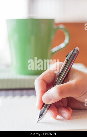 Hand writing on notebook in coffee shop Stock Photo