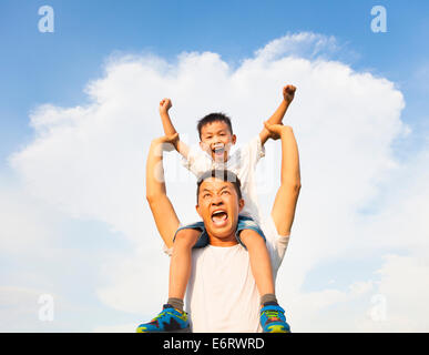 happy little boy sitting on father's shoulder Stock Photo