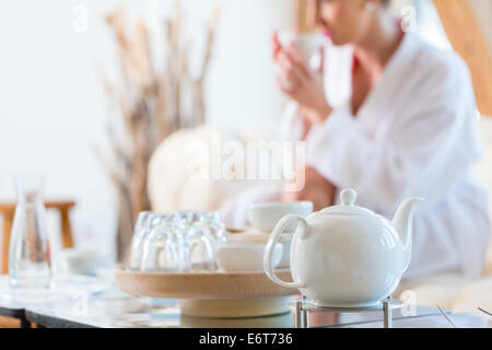 Woman in bath robe drinking tea in wellness spa relaxation room Stock Photo