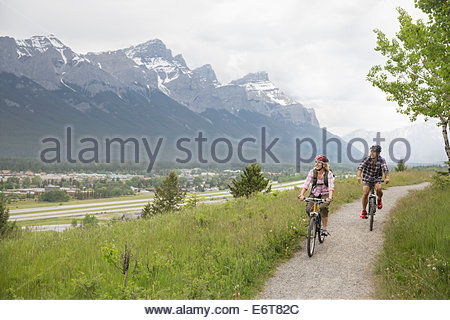 Couple riding mountain bikes on hillside
