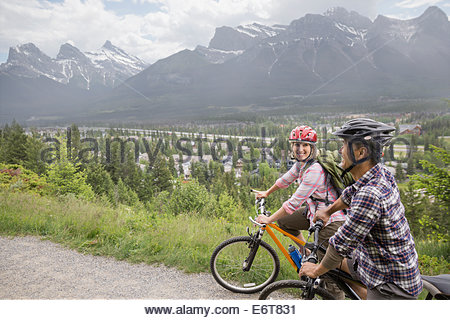 Couple riding mountain bikes on hillside