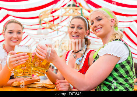 Friends drinking together Bavarian beer in national costume or Dirndl on Oktoberfest Stock Photo