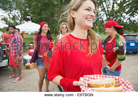 Woman eating hot dog at barbecue in field