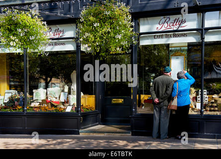 Senior couple reading menu outside Betty's cafe in Ilkley, North Yorkshire, England UK Stock Photo