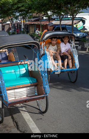 Yogyakarta, Java, Indonesia. Man and Woman Riding in a Becak, a Three-wheeled Vehicle Powered by Human Propulsion.  Malioboro St Stock Photo