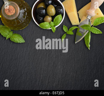 Ingredients of italian cuisine  - basil, parmesan, olives  and olive oil - on dark background Stock Photo