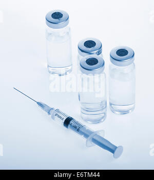 Glass Medicine Vials and botox, hualuronic, collagen or flu Syringe on a blue background. Stock Photo