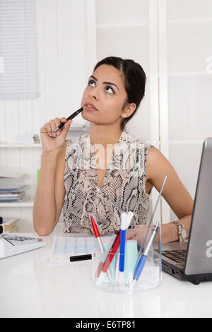 Sad, pensive and dreaming young woman sitting in the office. Concept for problems at work. Stock Photo