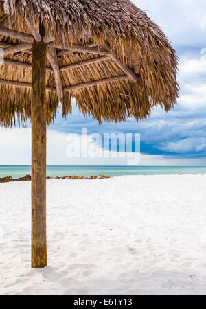 Thatch Umbrella on beach in Naples, Florida with storm rolling in over gulf. Stock Photo