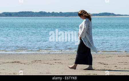 pregnant woman walking on the beach with teh sea as background Stock Photo