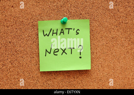Green post-it note saying "What's next?" on cork board (bulletin board). Close-up. Stock Photo