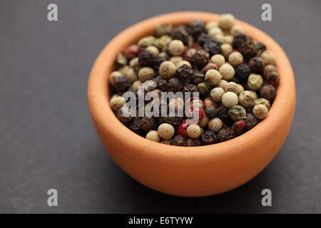 Mixed peppercorns in a bowl on black background. Closeup. Stock Photo