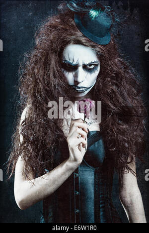 Woman in image of a gothic freak clown with withered flower. Grunge texture effect