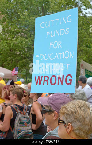 Asheville, North Carolina, USA - August 4, 2014:  Woman at a Moral Monday rally holds a sign protesting cuts in education amid a Stock Photo
