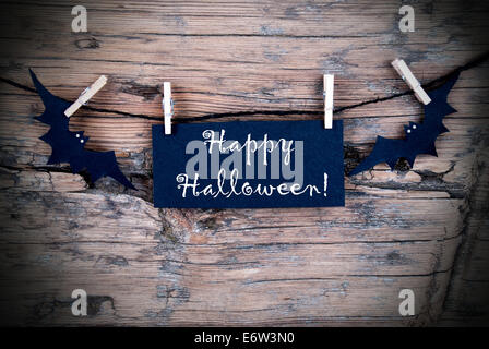 Black Label on a line with Happy Halloween on it, Wooden Background Stock Photo
