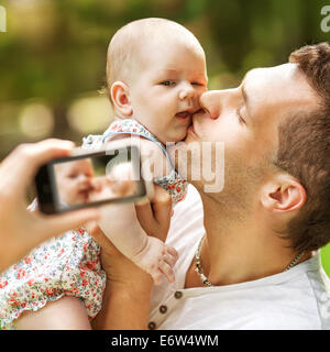 Family with baby In Park taking selfie by mobile phone Stock Photo