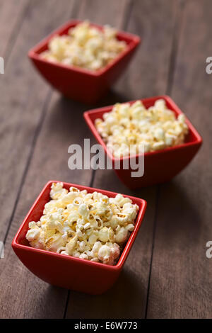 Three red bowls of freshly prepared salted popcorn (Selective Focus, Focus into the middle of the popcorn in the first bowl) Stock Photo