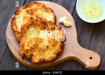 Freshly prepared traditional Hungarian deep fried flat bread called Langos made of a yeast dough Stock Photo