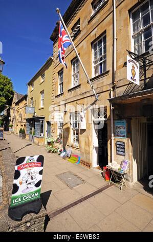 Union Jack flag on a flagpole attached the wall of a shop along the High Street, Chipping Campden, England, UK. Stock Photo