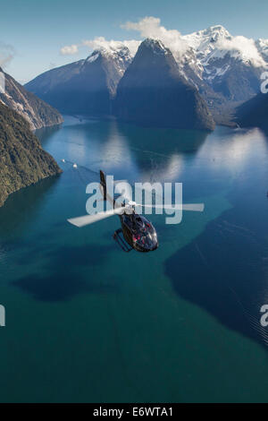 Aerial view of Milford Sound with helicopter below, Mitre Peak, Fiordland National Park, South Island, New Zealand Stock Photo