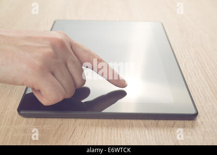 Female index finger pressing touch screen of digital tablet computer. Stock Photo
