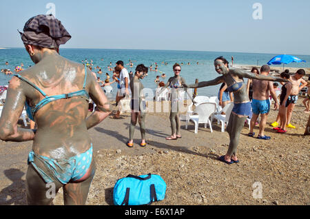 People are rubbing themselves with clay on the Dead Sea Coast, Israel Stock Photo