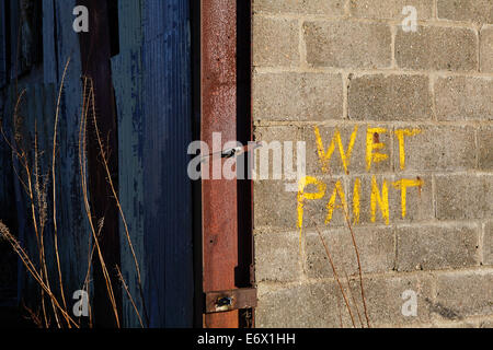 Old wet paint sign on concrete block wall of derelict building