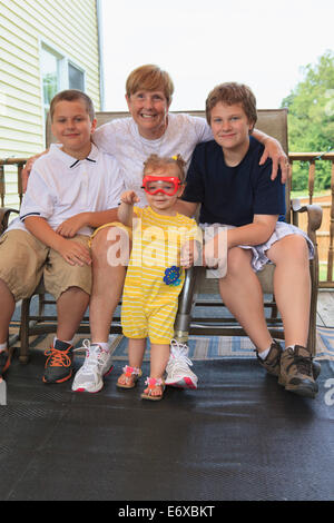 Grandmother with a prosthetic leg with her grandchildren sitting on their outdoor patio Stock Photo