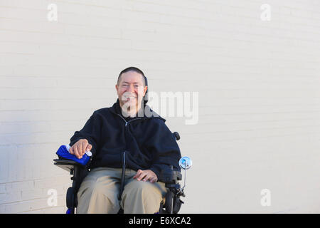 Man with spinal cord injury and arm with nerve damage in motorized wheelchair Stock Photo