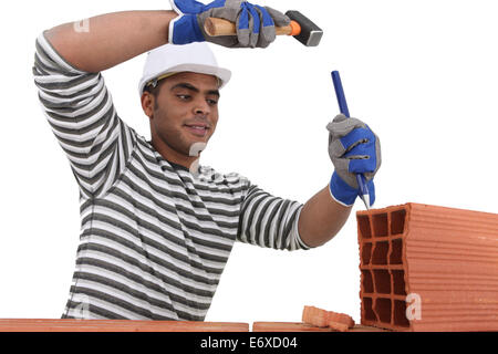 Mason using chisel on brick Stock Photo
