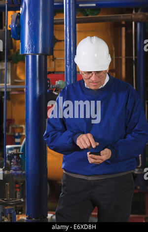 Power plant engineer in demineralization equipment room using smart phone Stock Photo