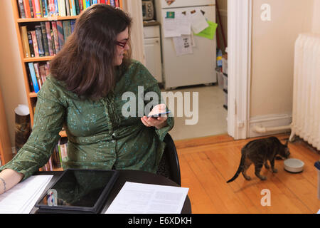 Woman with Asperger syndrome working in her home office and watching her cat Stock Photo