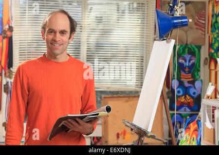 Man with Aspergers holding his reference material for his painting in an art studio