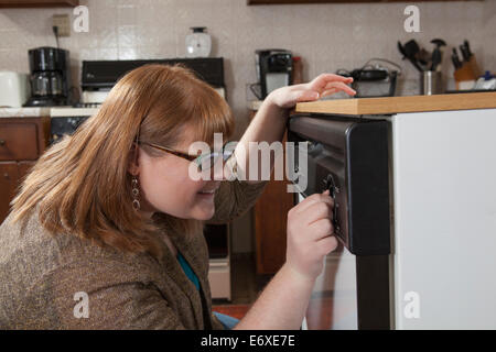 Woman who is legally blind starting the dishwasher in her kitchen Stock Photo