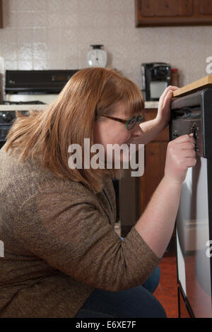 Woman who is legally blind starting the dishwasher in her kitchen Stock Photo
