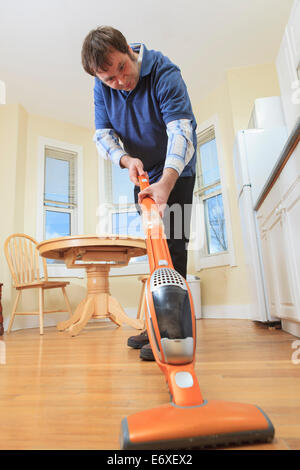 Man with Aspergers living in his home and vacuuming Stock Photo
