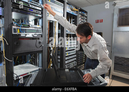 Data engineer holding laptop while working with supercomputer in server ...