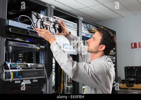 Network engineer putting rack mounted coaxial switches in place Stock Photo