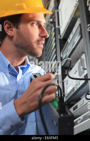 Network engineer installing cable equipment in rack Stock Photo