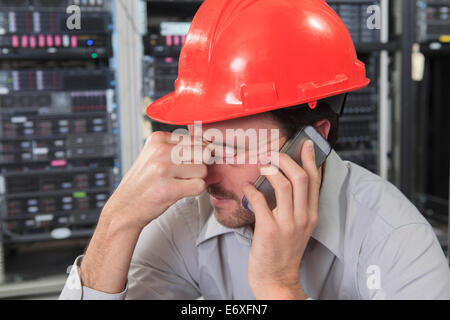 Network engineer rubbing eyes while using smart phone Stock Photo