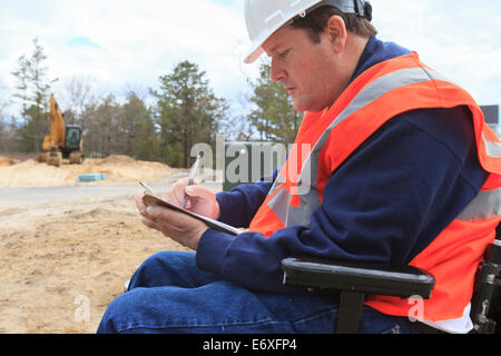 Construction engineer with spinal cord injury making notes at the site Stock Photo