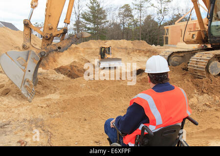 Construction engineer with spinal cord injury inspecting new foundation hole Stock Photo
